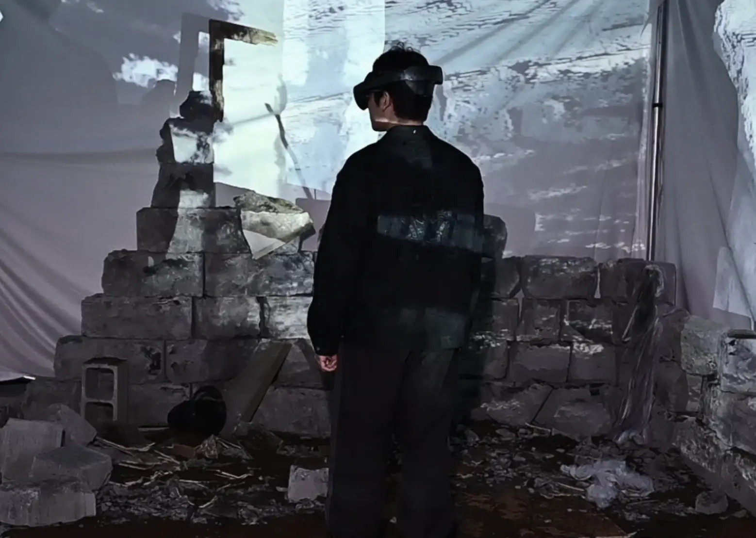The player in the physical set — a broken breeze-block wall and debris under projected ruins