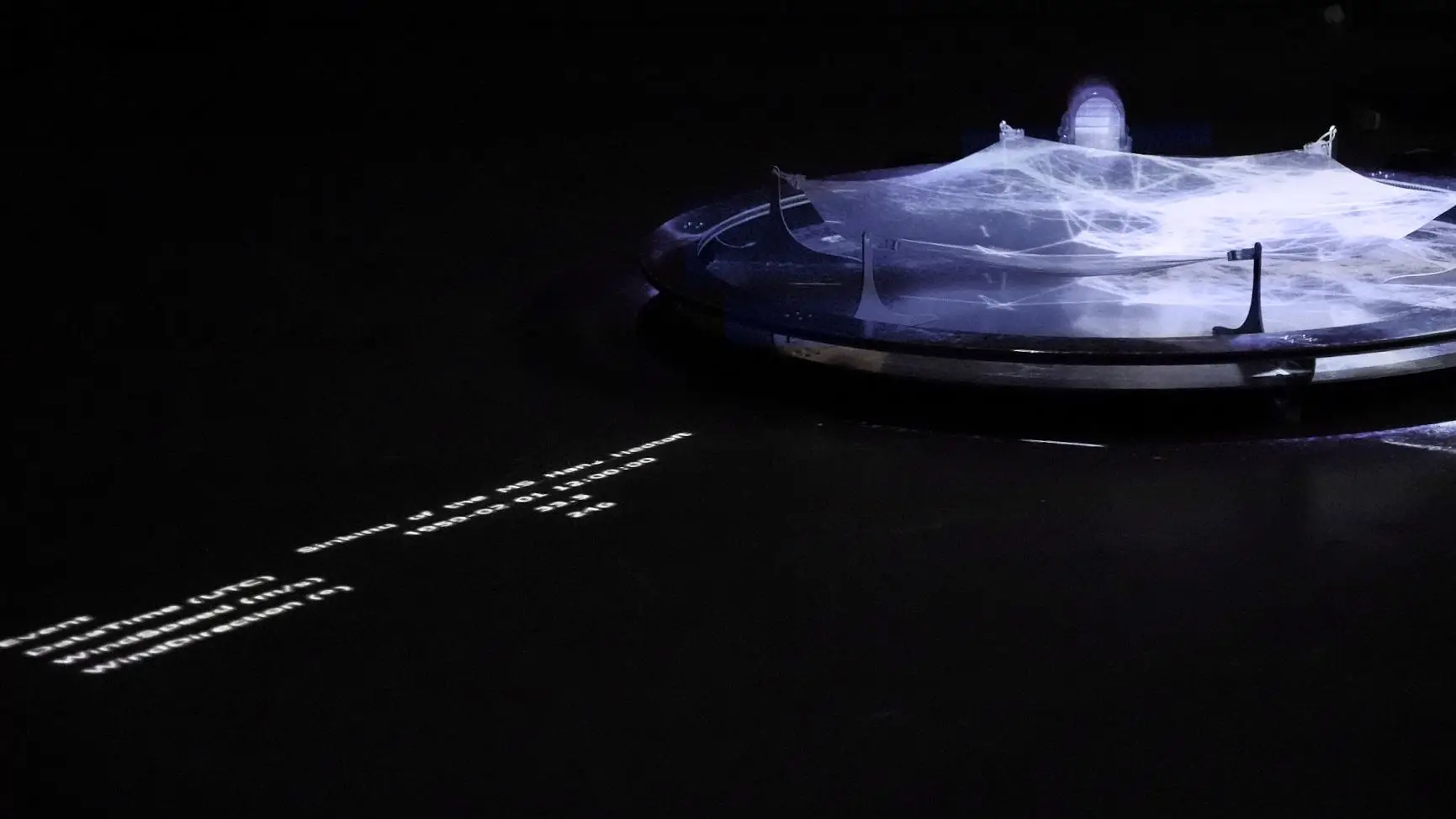 Detail of the ring structure and drive unit of The Dissonance of Wind under projected light