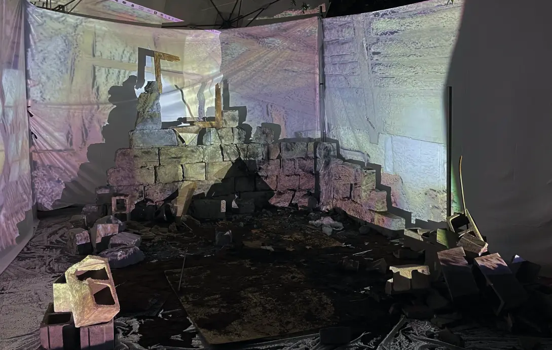 The installation without a player: curved projection screens around a ruined wall and rubble floor