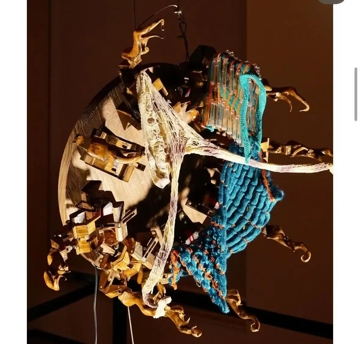 Close-up of Knitting Echoes — articulated wooden arms carrying knitted textile