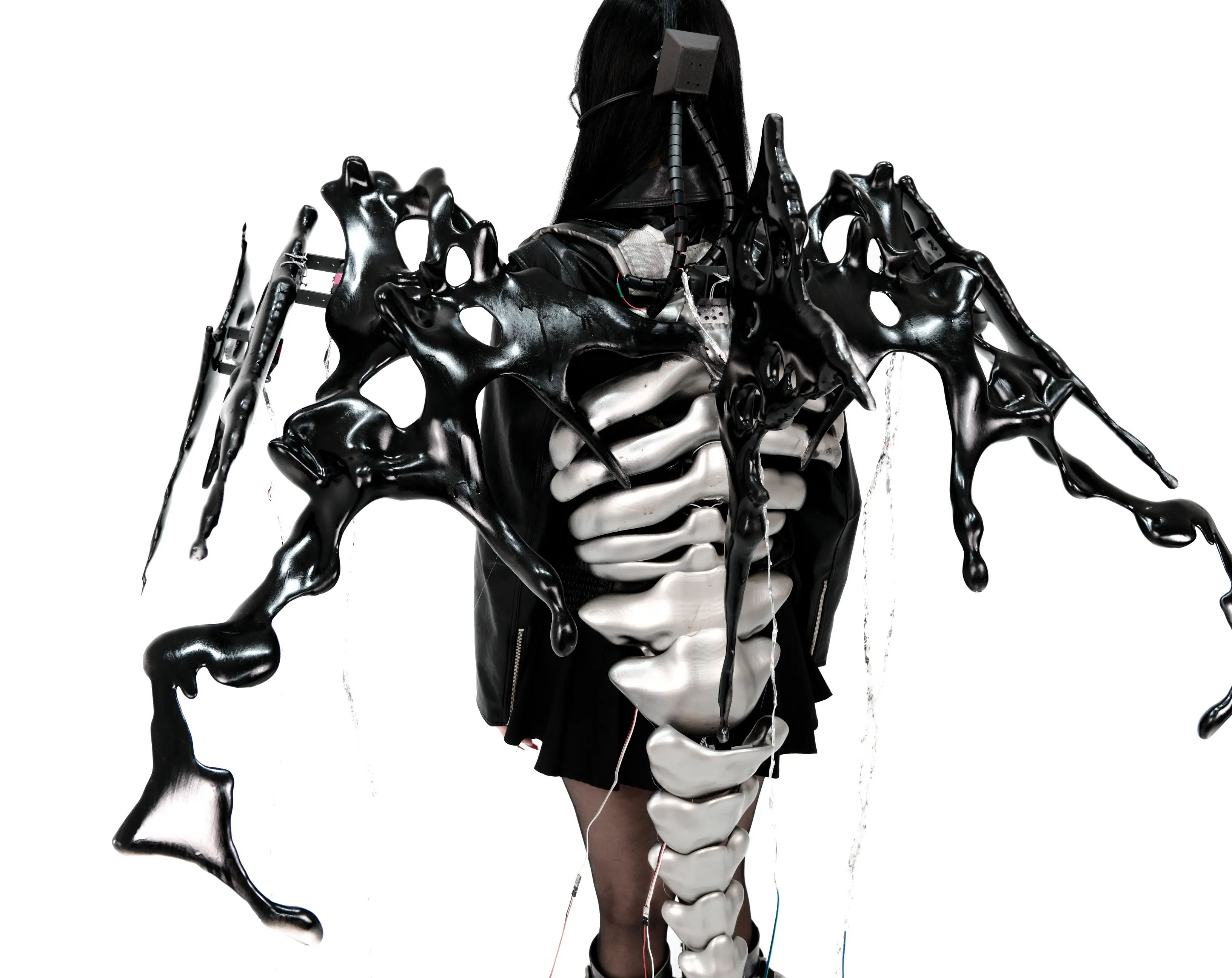 AetherWings wearable exoskeleton — black wing shells spread from the shoulders over a silver spine and ribcage
