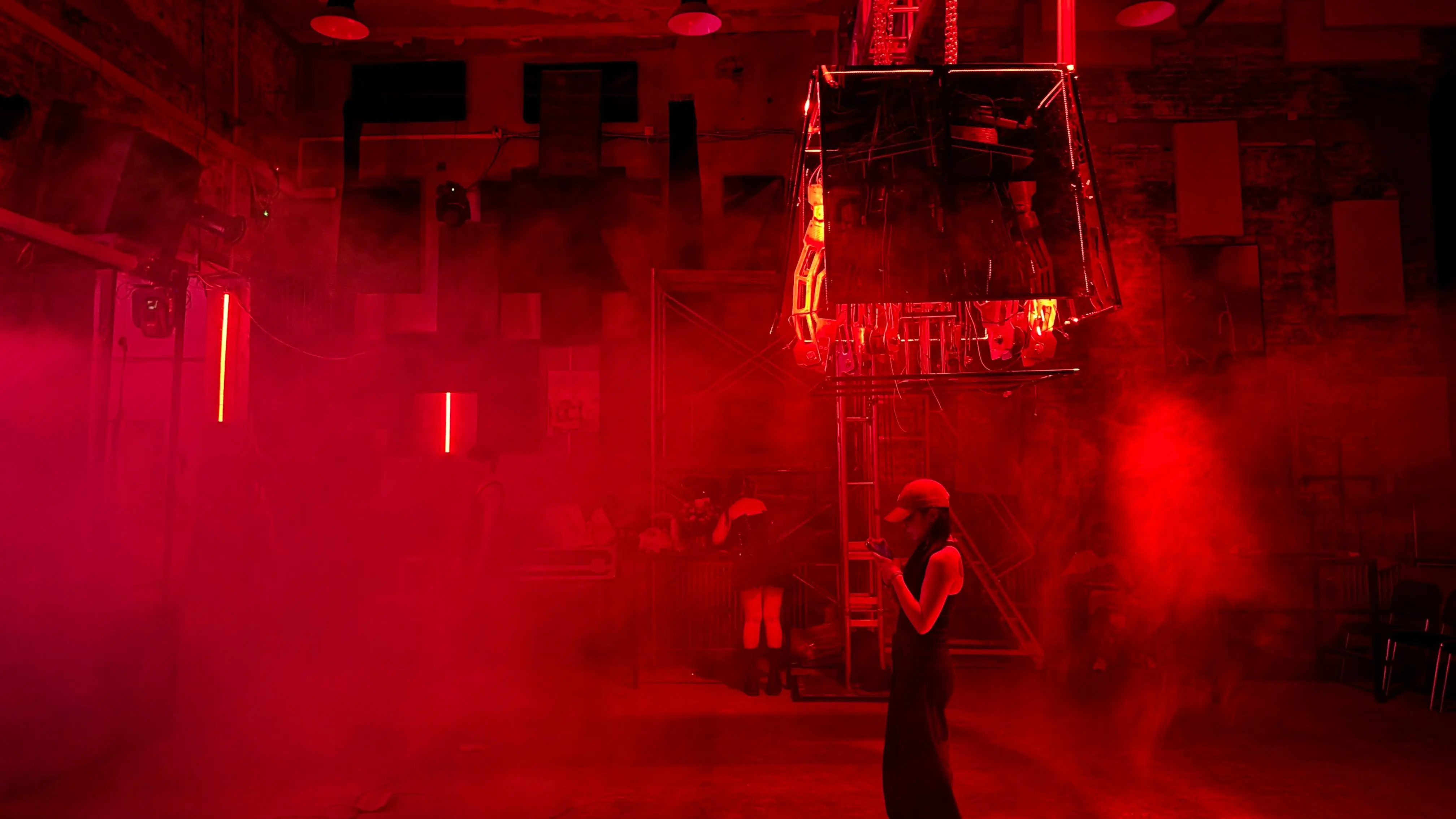 Blackbox hanging in a red-lit hall with audience below